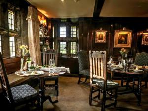 a dining room with tables and chairs and windows at Holdsworth House Hotel in Halifax