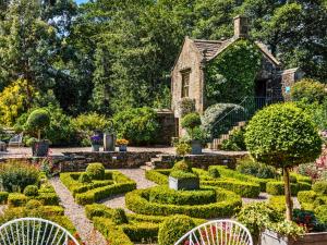 a garden with bushes and hedges in front of a house at Holdsworth House Hotel in Halifax