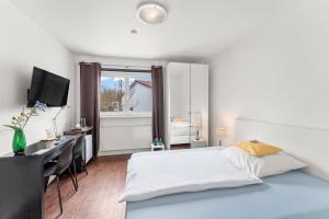 a bedroom with a bed and a desk and a window at ParkVilla Puschendorf, 24-7 Self-Check-in in Puschendorf
