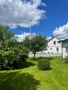 a yard with a white house and a fence at Familievennlig fritidsbolig i hjertet av Flå, perfekt for besøk i Bjørneparken in Flå