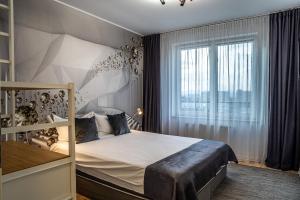 a bedroom with a bed and a large window at Cliché Luxury Apartment in Braşov