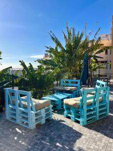 a group of blue tables and chairs with the beach in the background at Lazareto 148 Hostel in Funchal