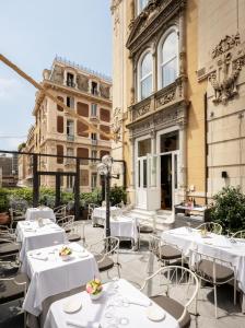 a restaurant with white tables and chairs in front of a building at Hotel Bristol Palace in Genoa