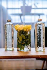 two glass bottles sitting on a table with yellow roses at Cliché Luxury Apartment in Braşov