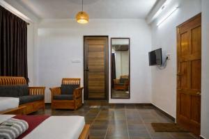 a room with a bed and a tv and a couch at Aroha luxury homestay in Madikeri