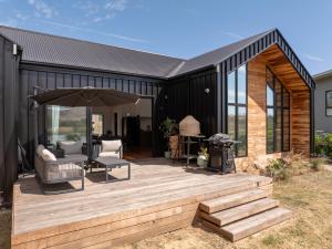 a black house with a wooden deck and an umbrella at The Barn Bonnie Doon in Bonnie Doon