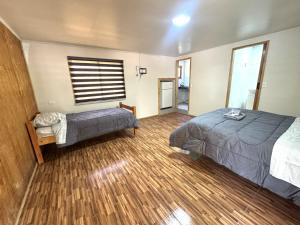 a bedroom with two beds and a window and wooden floors at Agro Camping Los Costeños in Choapa +17 photos
