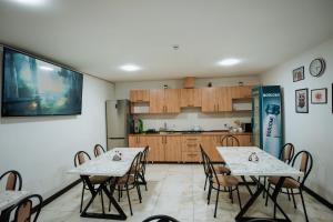 two tables and chairs in a room with a kitchen at Азия Hostel in Shymkent
