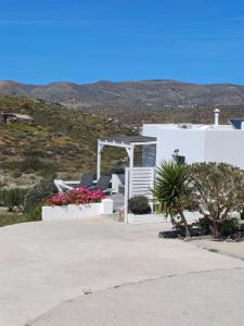 a white house with chairs and flowers on a hill at Romantic House Sea View Adults only in Ios Chora