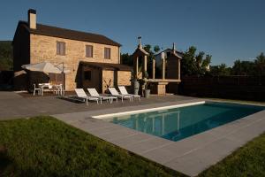 a swimming pool with chairs and a table and a house at ACASADETEO in Padrón