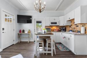 a kitchen with white cabinets and a table with stools at Suite Flamingo Pointe with Shared POOL in Bay Saint Louis