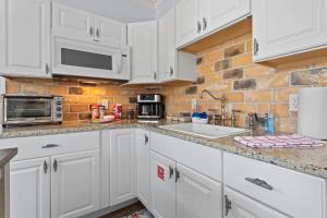 a kitchen with white cabinets and a brick wall at Suite Flamingo Pointe with Shared POOL in Bay Saint Louis