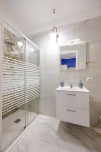 a white bathroom with a sink and a shower at Nalusa - al centro della riviera di chiaia in Naples