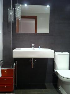 a bathroom with a sink and a toilet and a mirror at Duplex Torico Amantes in Teruel