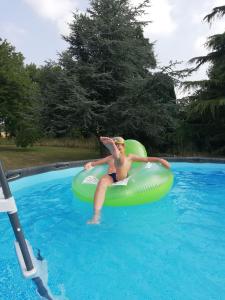 a woman riding on an inner tube in a swimming pool at Murmure de Tilleul in Alembon
