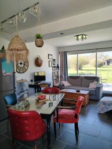 a living room with a table and red chairs at Murmure de Tilleul in Alembon