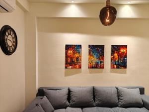 a living room with a couch and four paintings on the wall at Your Inn in Tríkala