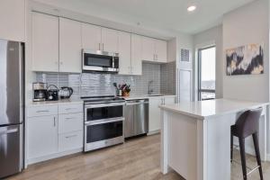 a kitchen with white cabinets and stainless steel appliances at Spacious Apt Downtown in Quincy