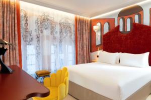 a bedroom with a large white bed and a desk at Hôtel Le Magnifique Ex Hôtel Le M in Paris