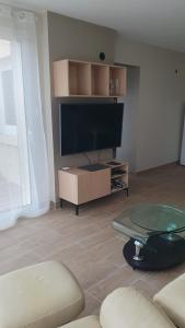 a living room with a flat screen tv and a table at le pied des monts in Sainte-Consorce