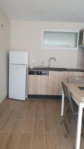 a kitchen with a white refrigerator and a table at le pied des monts in Sainte-Consorce