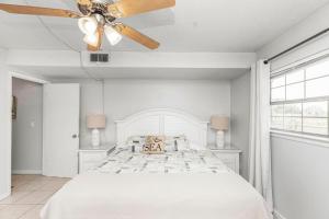 a white bedroom with a bed and a ceiling fan at Islandwood in Fort Walton Beach