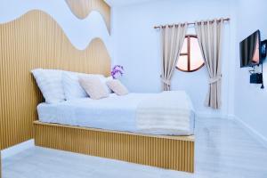 a bedroom with a bed with white sheets and a window at เพลินวิวโขงรีสอร์ท Plearnviewkhongresort in Ban Nong Mum