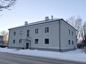 a large white building in the snow next to a road at Otepää city view apartment in Otepää