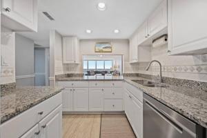 a kitchen with white cabinets and a sink at Oceanfront Condo/ Pool/ Surfing/ Fishing / EW 1002 in Virginia Beach