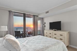 a bedroom with a bed and a flat screen tv at Oceanfront Condo/ Pool/ Surfing/ Fishing / EW 1002 in Virginia Beach