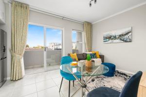 a living room with a glass table and blue chairs at The Orion 16 in Table View
