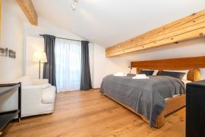 a bedroom with a large bed and a white chair at Ferienwohnung Dorfmitte in Reit im Winkl