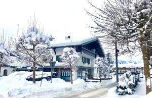 a building covered in snow with trees in front of it at Ferienwohnung Dorfmitte in Reit im Winkl