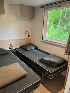 two beds sitting in a room with a window at Camping 3 étoiles - Piscine - ccbfa0c in Saint-Mandé-sur-Brédoire +57 photos