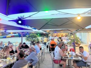 a group of people sitting at tables under umbrellas at Camping 3 étoiles - Piscine - ccbfa0c in Saint-Mandé-sur-Brédoire