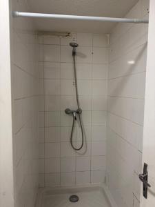 a shower with a hose in a white tiled bathroom at Apparemment 2 pièces in Vaulx-en-Velin +24 photos