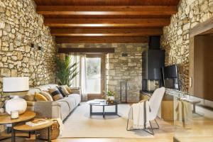 a living room with a couch and a stone wall at Villa Mas Summit in Collsuspina