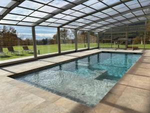 an indoor swimming pool with a glass ceiling at Villa Mas Summit in Collsuspina