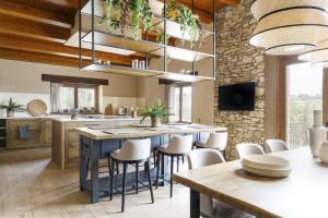 a kitchen with a large island with white stools at Villa Mas Summit in Collsuspina