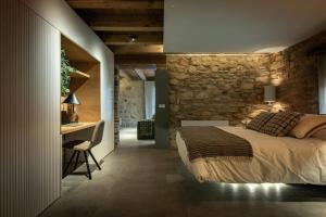 a bedroom with a stone wall and a bed and a desk at Villa Mas Summit in Collsuspina +34 photos