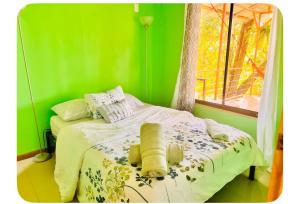 a green bedroom with a bed with towels on it at Mayra Campground in Savegre