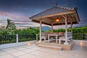a gazebo with a table and chairs on a patio at Puri Temple Villa in Canggu
