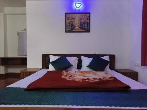 a bed with a red blanket and blue pillows at Rose Cottage in Devikolam