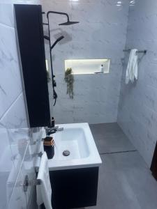a white bathroom with a sink and a mirror at Serenity Suite in Accra