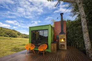 a green tiny house with a fireplace on a deck at Cabana estilo Glamping com Banheiras Quente e Vista às Montanhas in Rio do Sul