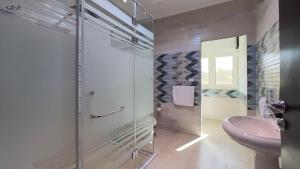 a bathroom with a glass shower and a sink at TriPyramids Suites in Cairo