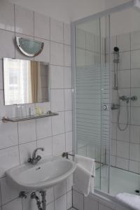 y baño blanco con lavabo y ducha. en Hotel Ohm Patt en Boppard