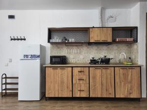 a kitchen with wooden cabinets and a white refrigerator at Torgai Hotel Apartments in Ureki