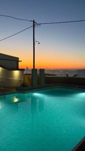 a swimming pool with a sunset in the background at Coralli Beach Hotel in Kokkini Khanion