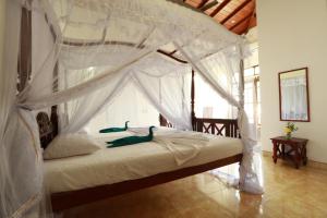 1 dormitorio con cama con dosel y cortinas blancas en Flamingo Guest house, en Unawatuna